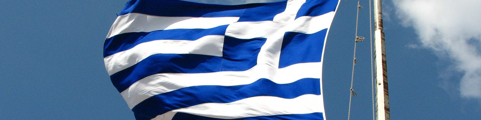 The flag of Greece being blown by wind from the Mediterranean Sea.