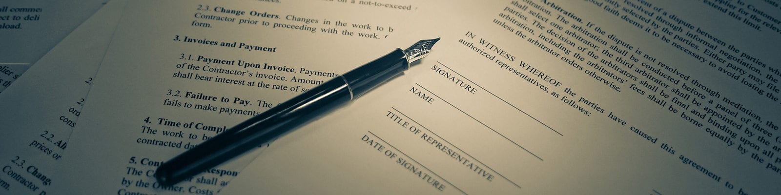 A printed, official contract with a pen resting on top of it.